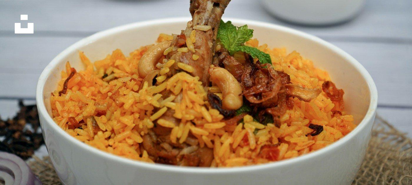A bowl of chicken biryani with herbs and spices