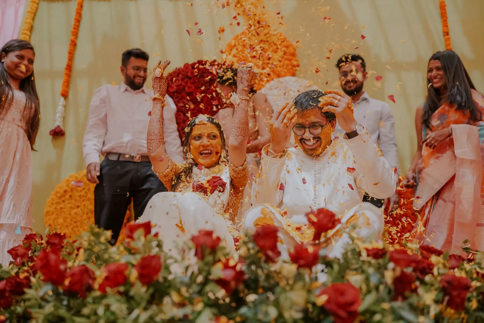 A joyful haldi celebration with flowers in the air; illustrative photograph